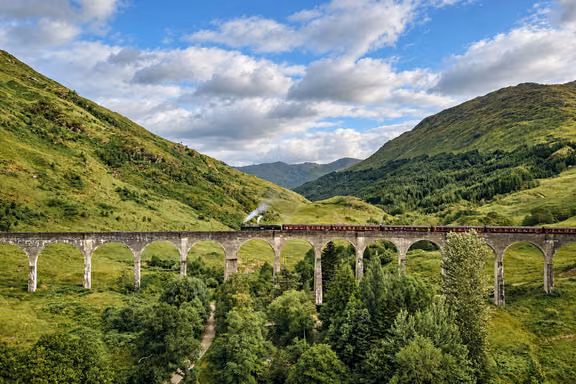 The curved arches of the Glenfinnan Viaduct in a green glen