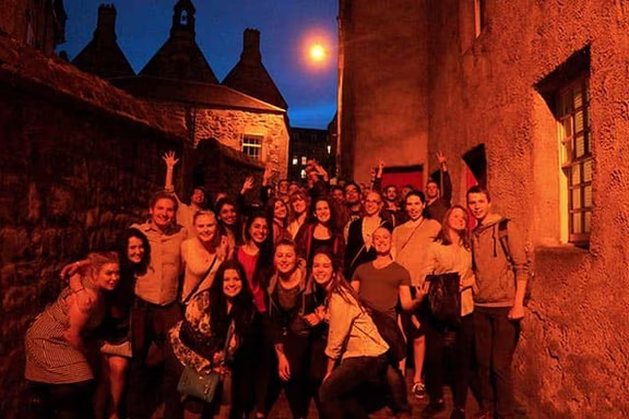 Grupo del pub crawl en un callejón de la Old Town de noche